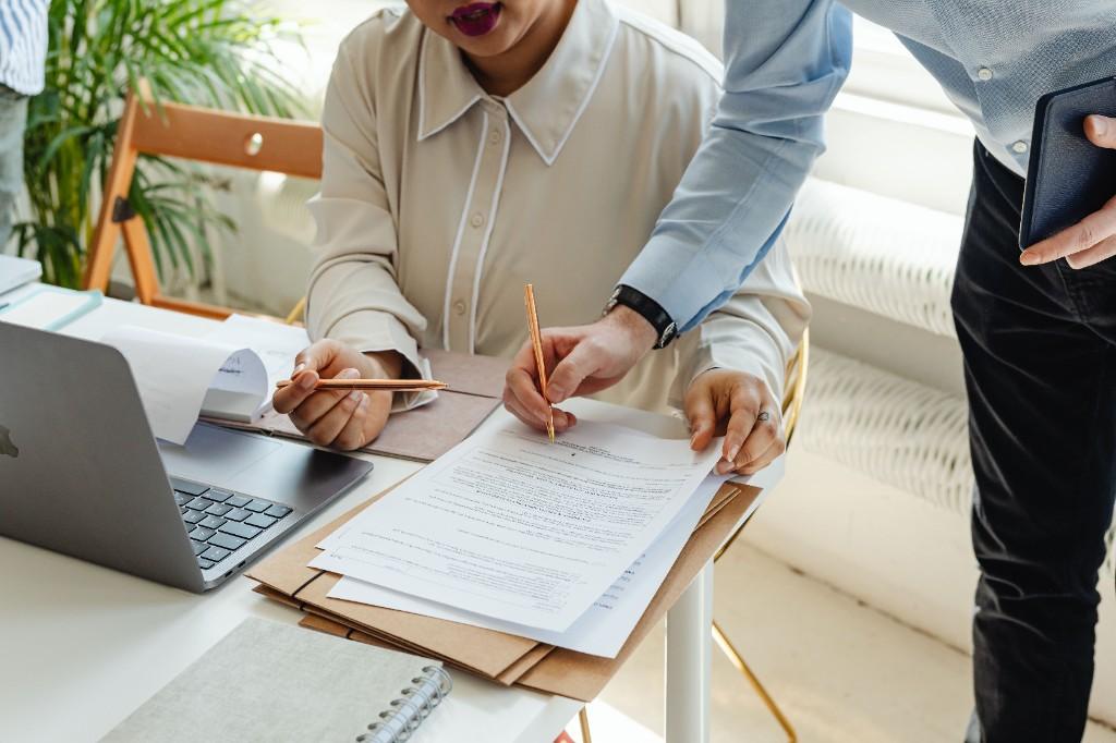 Two professionals reviewing and annotating formal documents at a bright office desk
